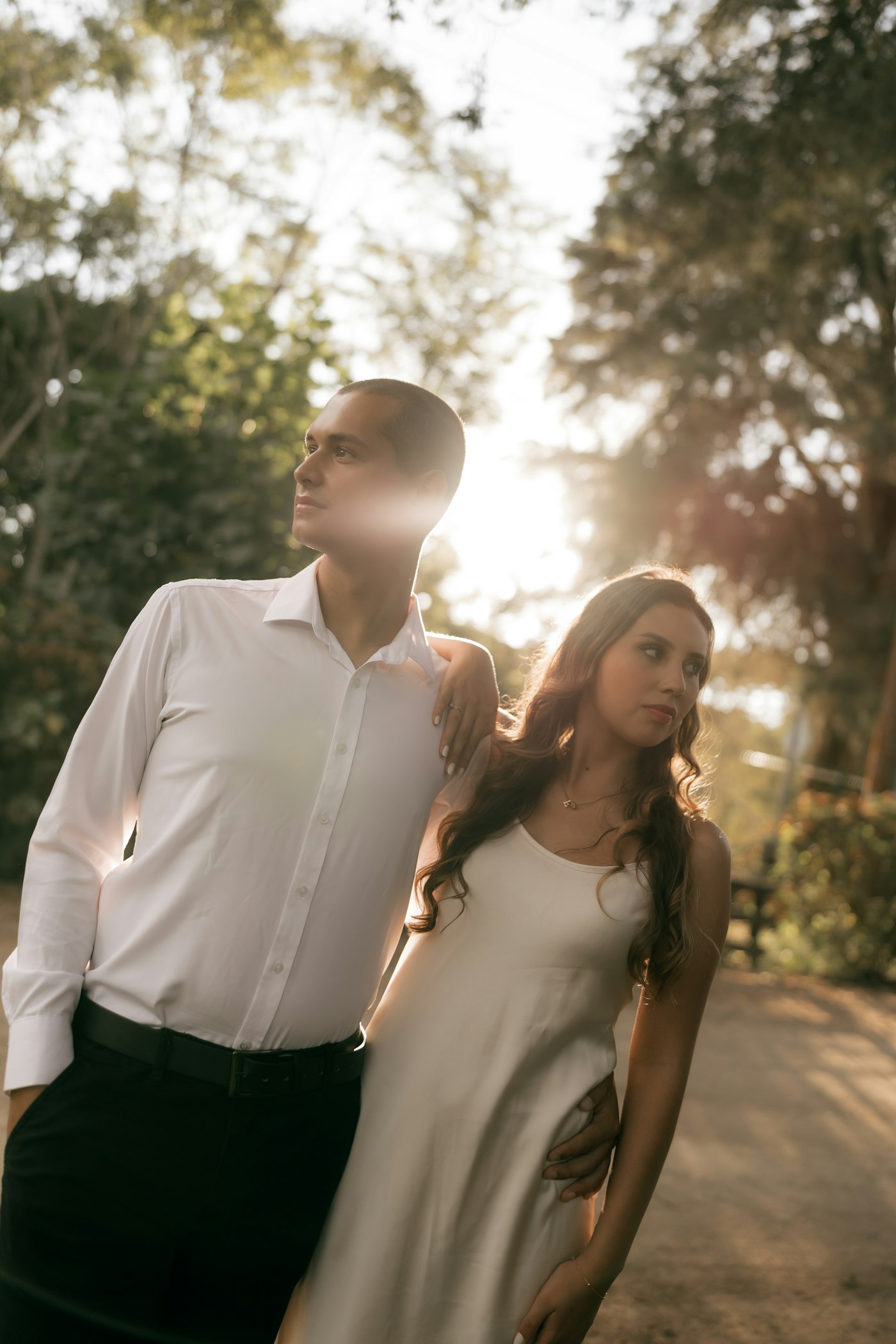 Couple posing outdoors with sunlight filtering through trees