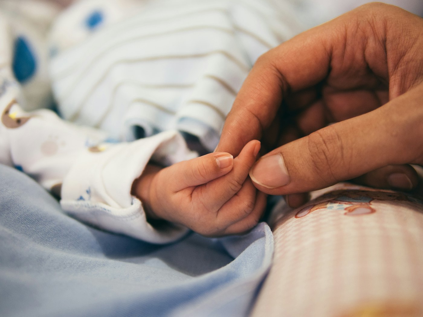Person holding baby's index finger