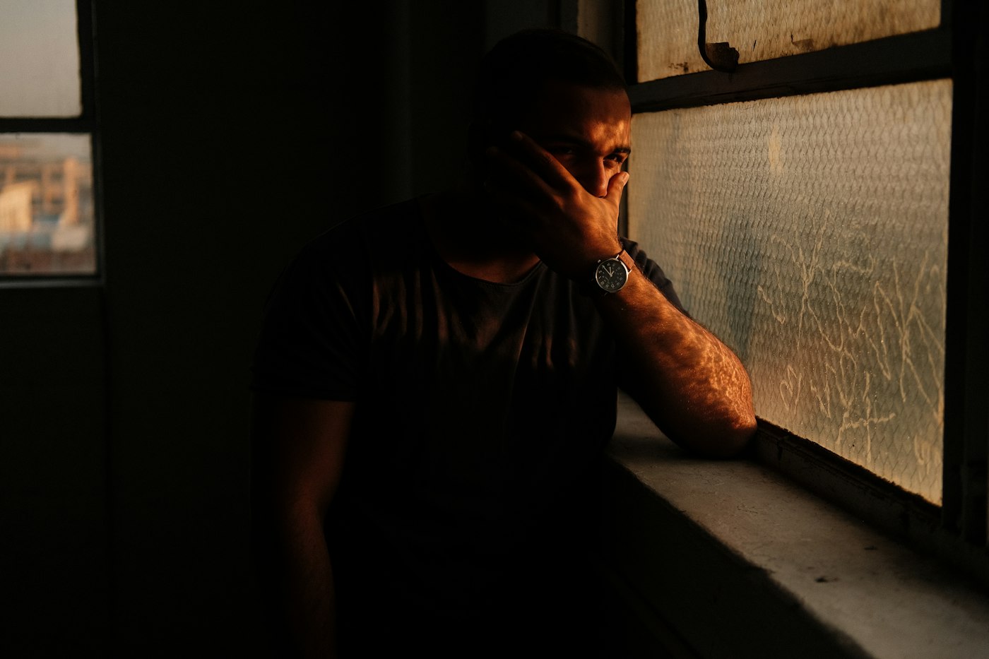 A man leaning against a window in a dark room