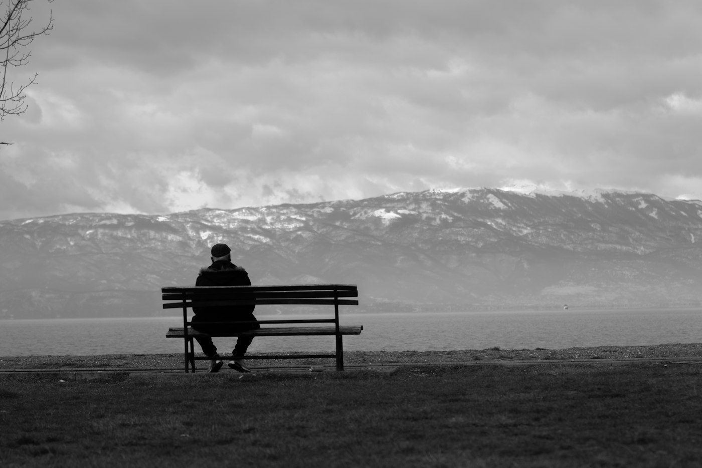 Grayscale photo of man sitting on bench